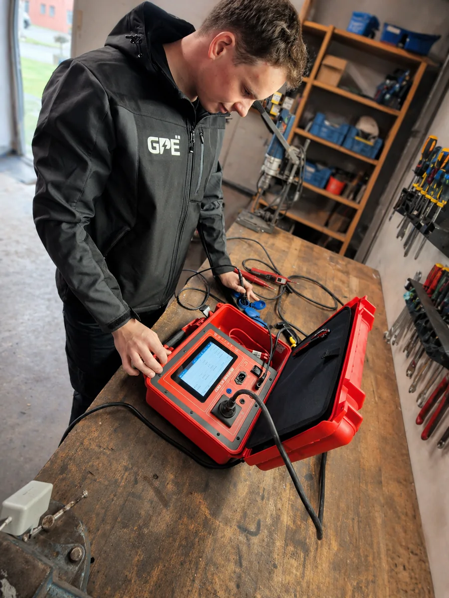 Robert Gericks in GPE-Jacke an der Werkbank beim Vorbereiten eines Benning Prüfgeräts